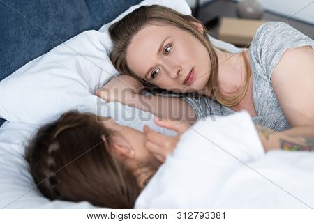 Selective Focus Of Two Lesbians Looking At Each Other While Lying In Bed