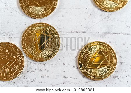 Golden Commemorative Eos - Eosio Cryptocurrency - Coins On White Stone Board, View From Above