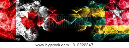 Canada Vs Togo, Togolese Smoky Mystic Flags Placed Side By Side. Thick Colored Silky Smoke Flags Of 