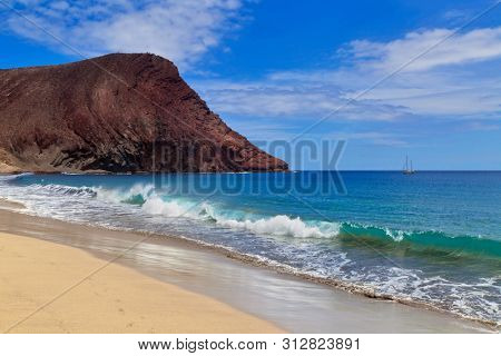 Atlantic Ocean with a sailing boat in the scene from La Tejita beach, Tenerife, Canary Islands, Spain.