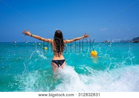 Ibiza beach girl splashing water open arms in Balearic islands