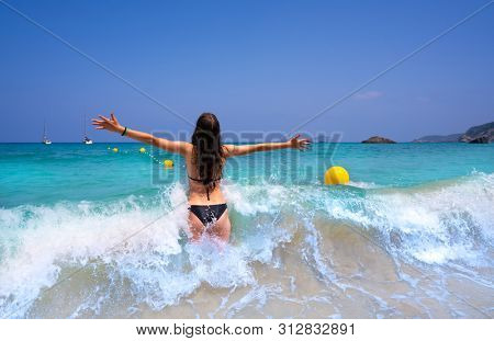 Ibiza beach girl splashing water open arms in Balearic islands