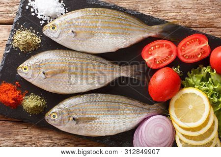 Freshly Caught Sarpa Salpa With Raw Vegetables And Spices Close-up On A Slate Board. Horizontal Top