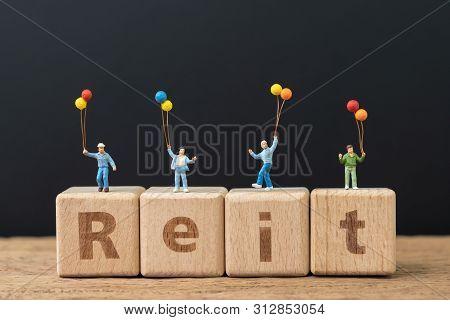 Reit, Real Estate Investment Trust Concept, Happy Miniature People Holding Balloons On Cube Wooden B