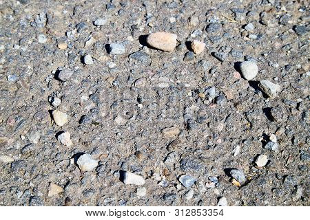 Stone Asphalt Texture Of Road And Pebbles Circle. Grey Asphalt Road And And A Hand-made Circle Of Gr