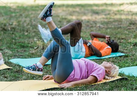 Selective Focus Of Senior Woman With Grey Hair And African American Man Working Out On Fintess Mats