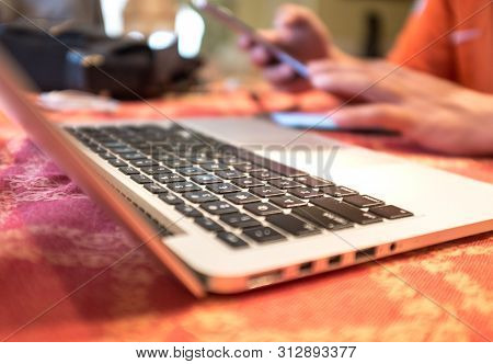 Hands On Smart Phone With Laptop On The Foreground. Flexi Work Concept.