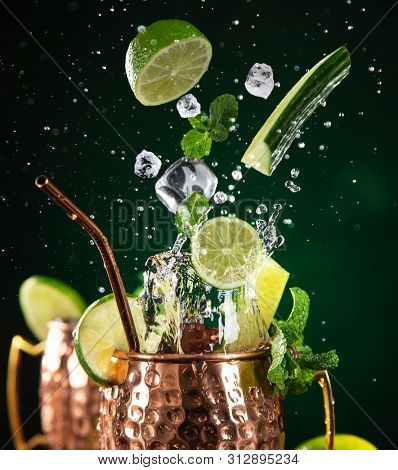 Famous splashing Moscow mule alcoholic cocktail in copper mugs, freeze motion effect.