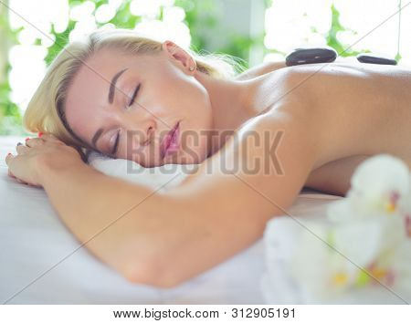 Young woman in spa salon, getting stones massage.