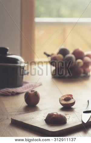 Making Peaches Jam On Wooden Table In Natural Light. Kitchen Table In Front Of Balcony Glass Door