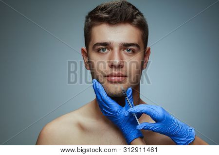 Close-up Portrait Of Young Man Isolated On Grey Studio Background. Filling Surgery Procedure. Concep