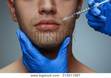 Close-up Portrait Of Young Man Isolated On Grey Studio Background. Filling Surgery Procedure. Concep