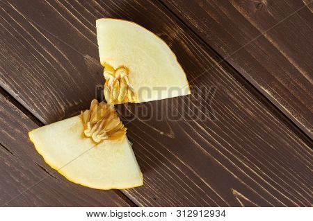 Group Of Two Pieces Of Fresh Yellow Melon Canary Copyspace On Right Flatlay On Brown Wood