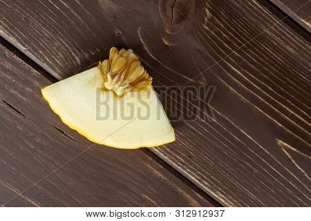 One Piece Of Fresh Yellow Melon Canary Flatlay On Brown Wood