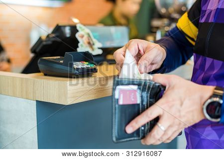 Selective Focus To Credit Card Reader With Blurry The Man Picking Up Banknotes Or Credit Card In The