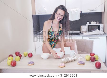 Happy Woman In Fashionable Swimsuit With Green Leaves Posing In White Kitchen