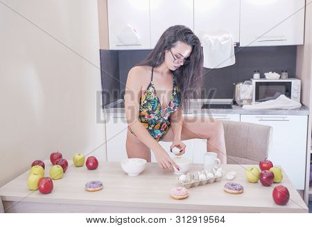 Happy Woman In Fashionable Swimsuit With Green Leaves Posing In White Kitchen