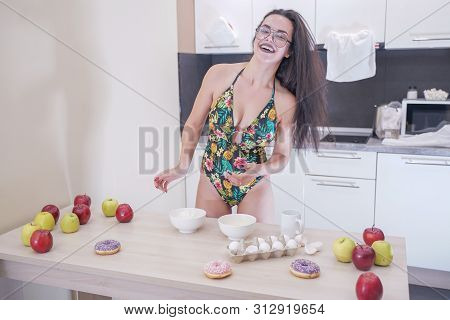 Happy Woman In Fashionable Swimsuit With Green Leaves Posing In White Kitchen