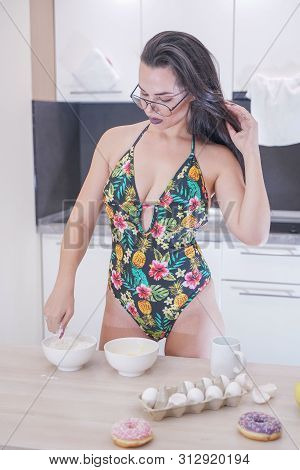 Happy Woman In Fashionable Swimsuit With Green Leaves Posing In White Kitchen
