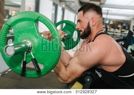 A Young Athlete Trains In The Gym. Trians Biceps Muscules