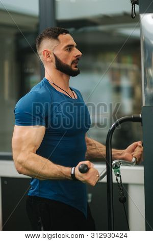 A Young Athlete Trains In The Gym. Trians Biceps Muscules