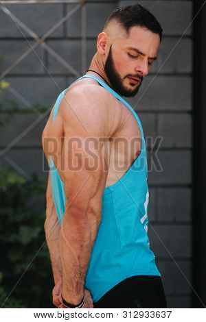 Handsome Bodybuilder In Blue Singlet Posing Outside. Bearden Men Before Training