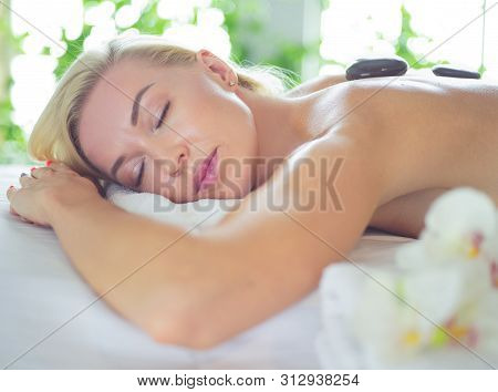 Young Woman In Spa Salon, Getting Stones Massage.