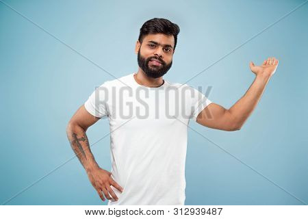 Half-length Close Up Portrait Of Young Hindoo Man In White Shirt On Blue Background. Human Emotions,