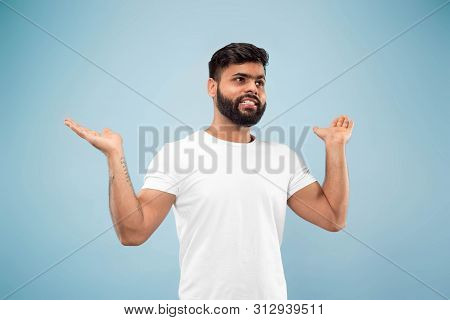 Half-length Close Up Portrait Of Young Hindoo Man In White Shirt On Blue Background. Human Emotions,