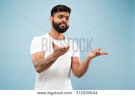 Half-length Close Up Portrait Of Young Hindoo Man In White Shirt On Blue Background. Human Emotions,