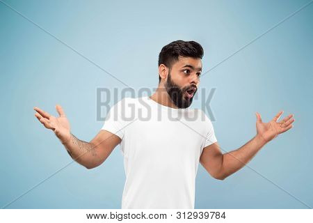 Half-length Close Up Portrait Of Young Hindoo Man In White Shirt On Blue Background. Human Emotions,