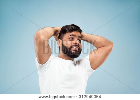 Half-length Close Up Portrait Of Young Hindoo Man In White Shirt On Blue Background. Human Emotions,