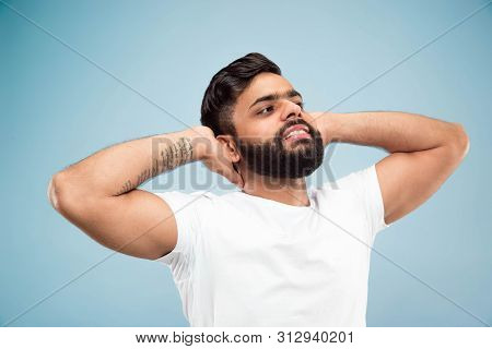 Half-length Close Up Portrait Of Young Hindoo Man In White Shirt On Blue Background. Human Emotions,