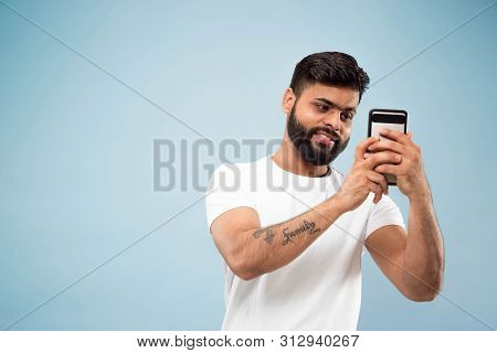 Half-length Close Up Portrait Of Young Hindoo Man In White Shirt On Blue Background. Human Emotions,