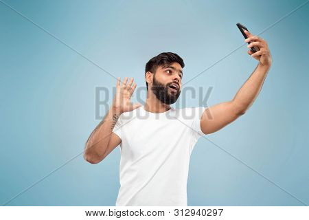 Half-length Close Up Portrait Of Young Hindoo Man In White Shirt On Blue Background. Human Emotions,