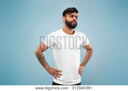 Half-length Close Up Portrait Of Young Hindoo Man In White Shirt On Blue Background. Human Emotions,