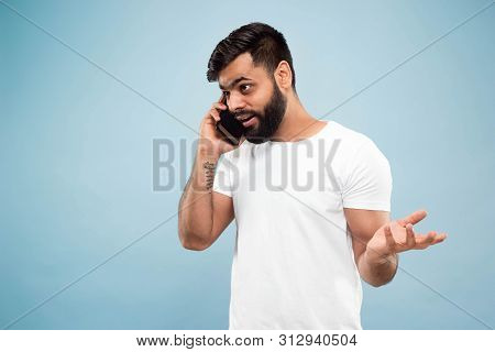 Half-length Close Up Portrait Of Young Hindoo Man In White Shirt On Blue Background. Human Emotions,