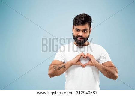 Half-length Close Up Portrait Of Young Hindoo Man In White Shirt On Blue Background. Human Emotions,