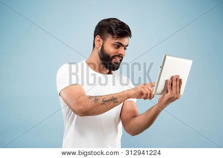 Half-length Close Up Portrait Of Young Hindoo Man In White Shirt On Blue Background. Human Emotions,