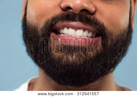 Close Up Portrait Of Young Hindoo Mans Face With Beard, White Teeth And Lips On Blue Background. Smi
