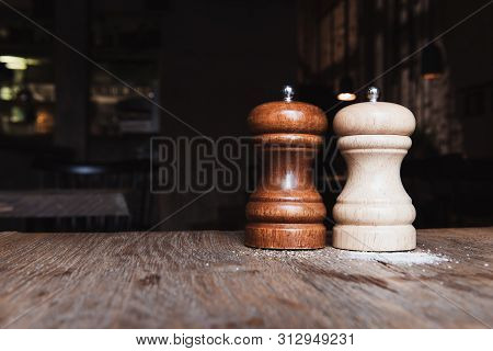 Wooden Salt And Pepper Mill On A Wooden Table In Dark Cafe. Copy Space. Salt And Pepper Shakers. Vin
