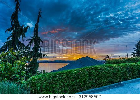 A Sunset With Clouds Behind A Rofftop In The Pacific Northwest.