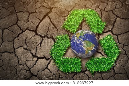 The Globe And The Recycled Logo That Rises From The Leaves Are Placed On The Ground That Is Broken -