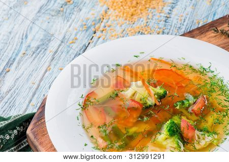 Vegetable Brot, Soup With Broccoli, Asparagus, Carrots, Onions, Bell Peppers And Greens In A White P