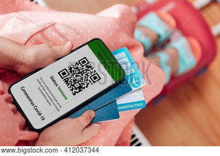 The girl holding the mobile phone a mockup for digital vaccination certificate in one hand and passport, mask and ticket in another one