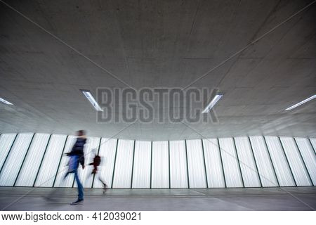 Motion blurred people - figures in an underpassage getting to their workplace in the morning. Busy city business life.