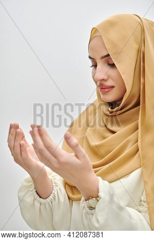Portrait of young muslim woman making dua, praying to God