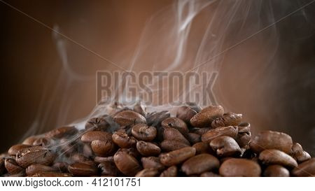 Falling Roasted Coffee Beans on Brown Background, close-up.