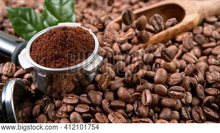 Falling Roasted Coffee Beans on Brown Background, close-up.