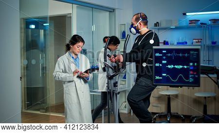 Sportsman With Mask Running On Cross Trainer In Sports Science Laboratory Measuring Vo2 Max, Heart R
